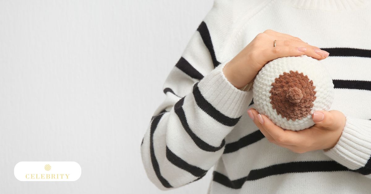 Close-up of a breast model held by a person in a white and black sweater, used to illustrate common concerns regarding when is nipple hair not normal.