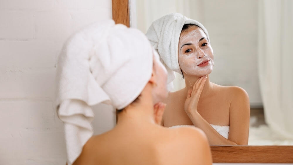 Woman is applying mask on her face