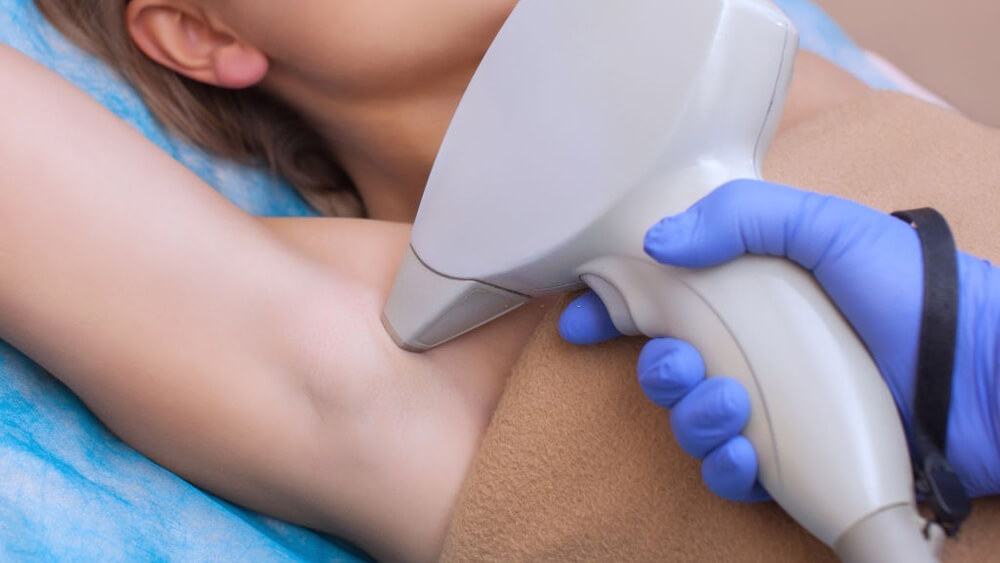 Cosmetologist does the laser hair removal procedure in the armpit zone