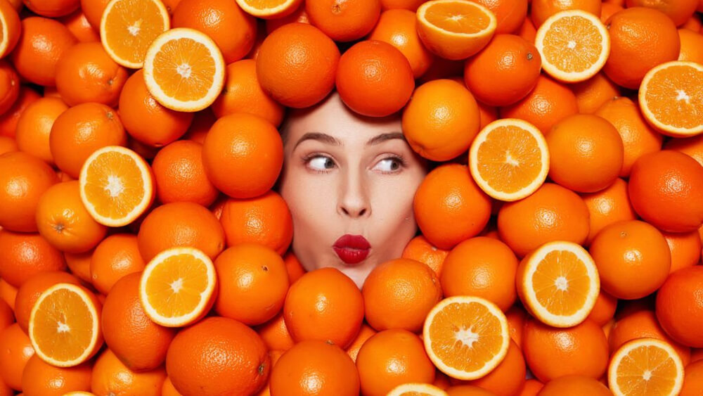 Delicious oranges as a symbol of vitamin C and face of a woman