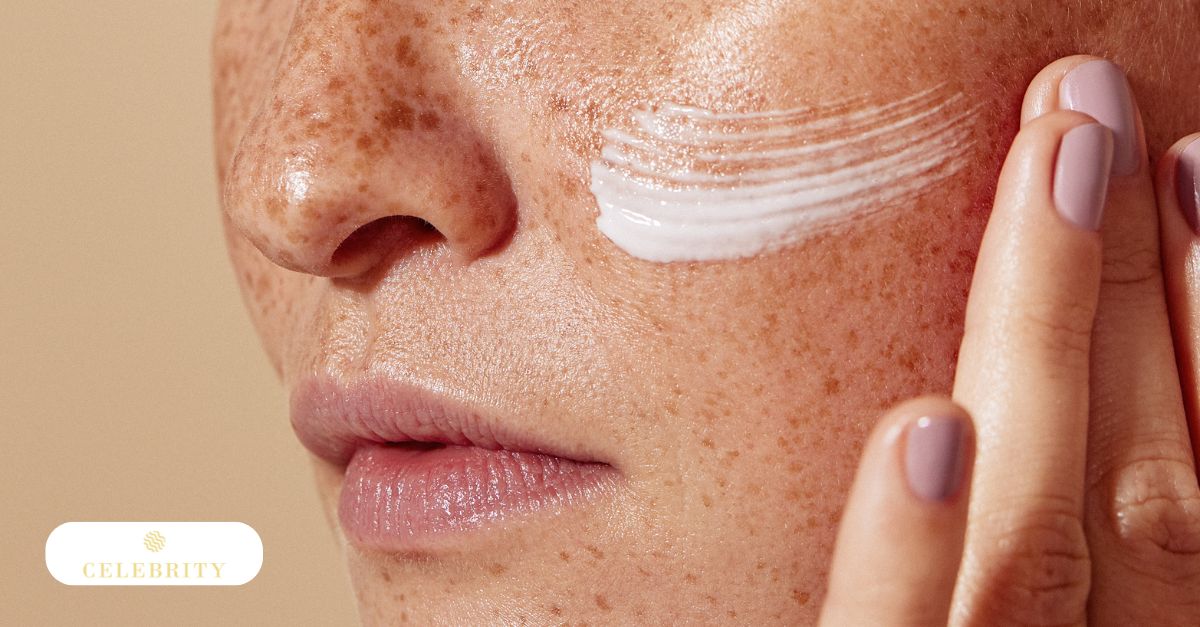 A close-up of a person applying sunscreen to a freckled cheek to demonstrate how to prevent freckles and brown spots from returning.
