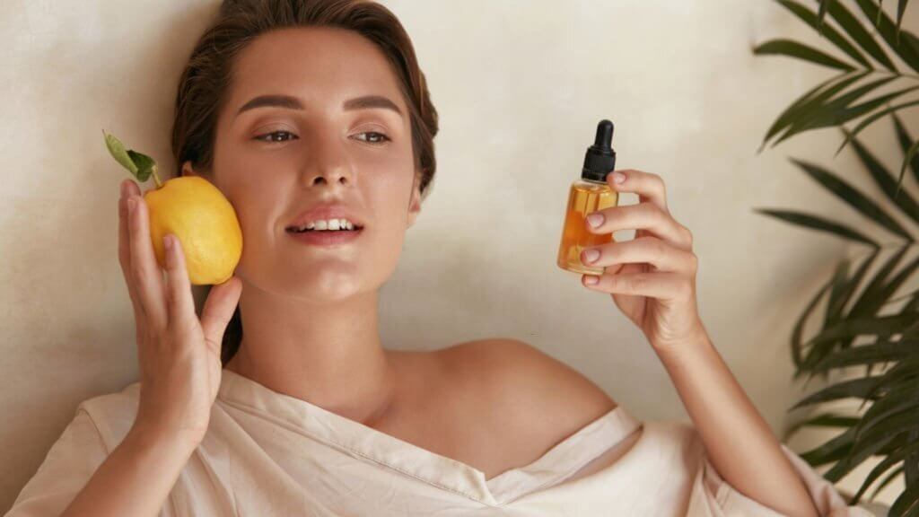 Woman holding lemon and bottle near face skincare