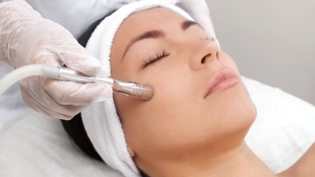 Cosmetologist does microneedling on facial skin