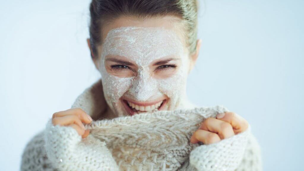 Happy woman with white facial mask playing with her clothes