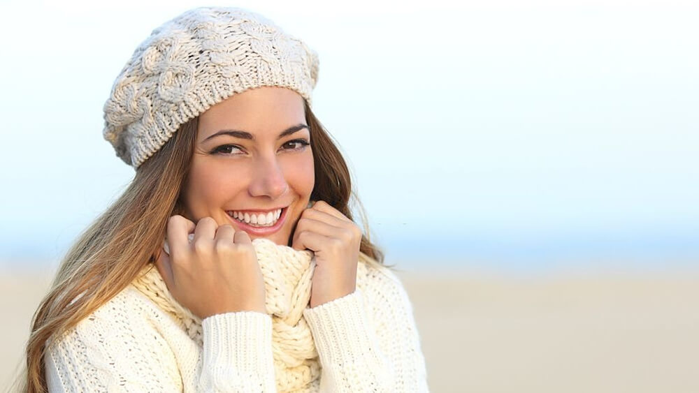 Woman smiles with a perfect white teeth in the winter