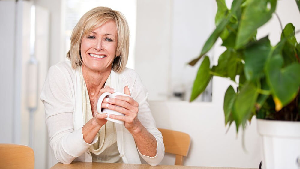 Cheerful middle-aged woman enjoying hot tea