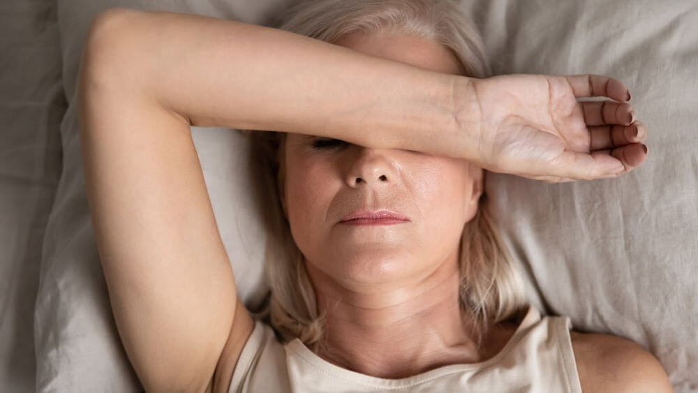 Melancholic woman lying with a hand on face feels unwell