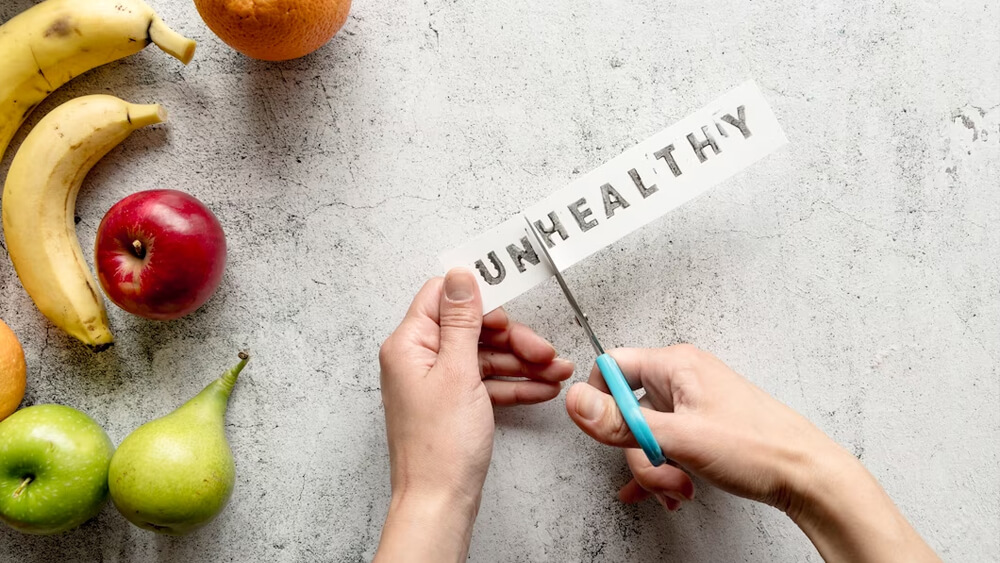 Cutting unhealthy word with scissor near healthy fruits