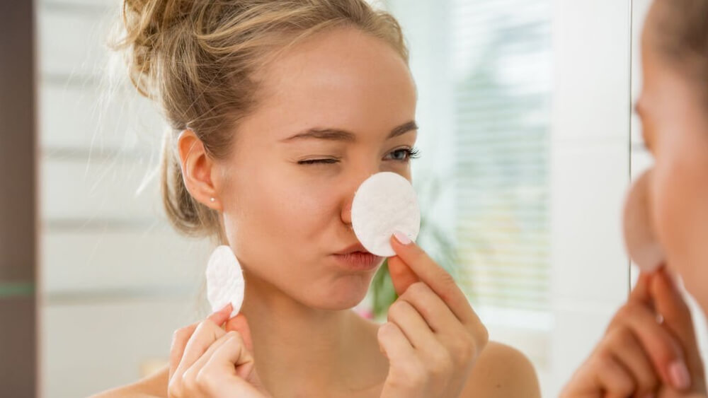 Woman cleaning her face skin with cotton pad