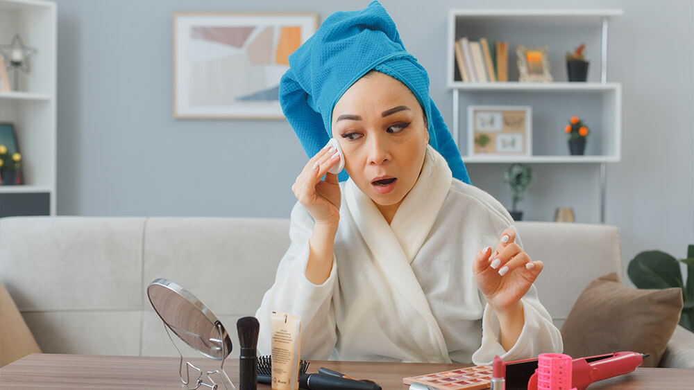 Young Asian woman with towel on her head doing makeup
