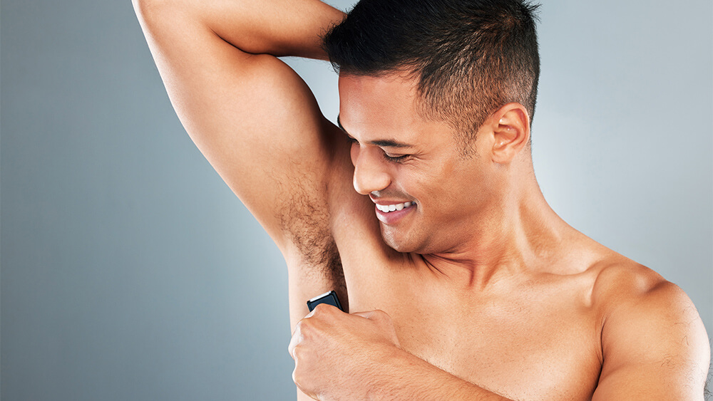Man with an electric shaver, doing armpit hair removal