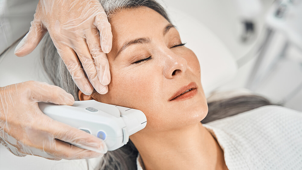 Pleased Asian patient enjoying the procedure of IPL on her face