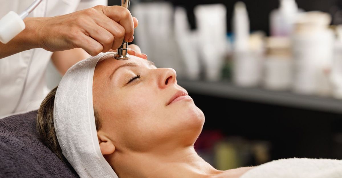 A technician using a microdermabrasion wand on a client's forehead to improve skin clarity.