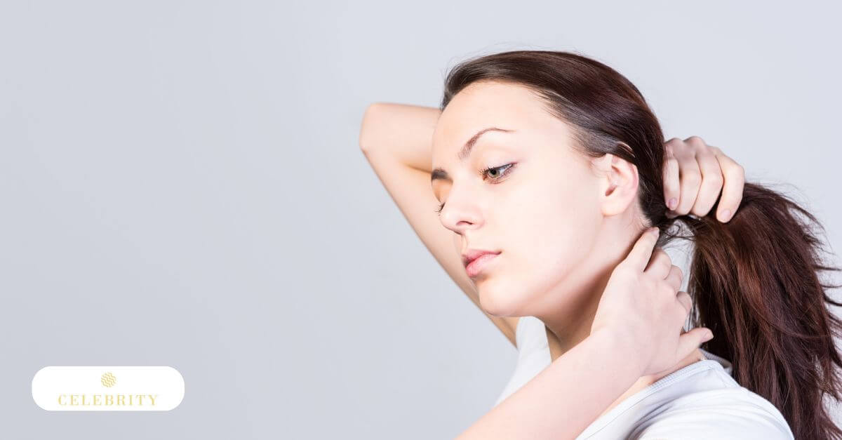 A young woman with her hair pulled back studies her bare skin after cleansing