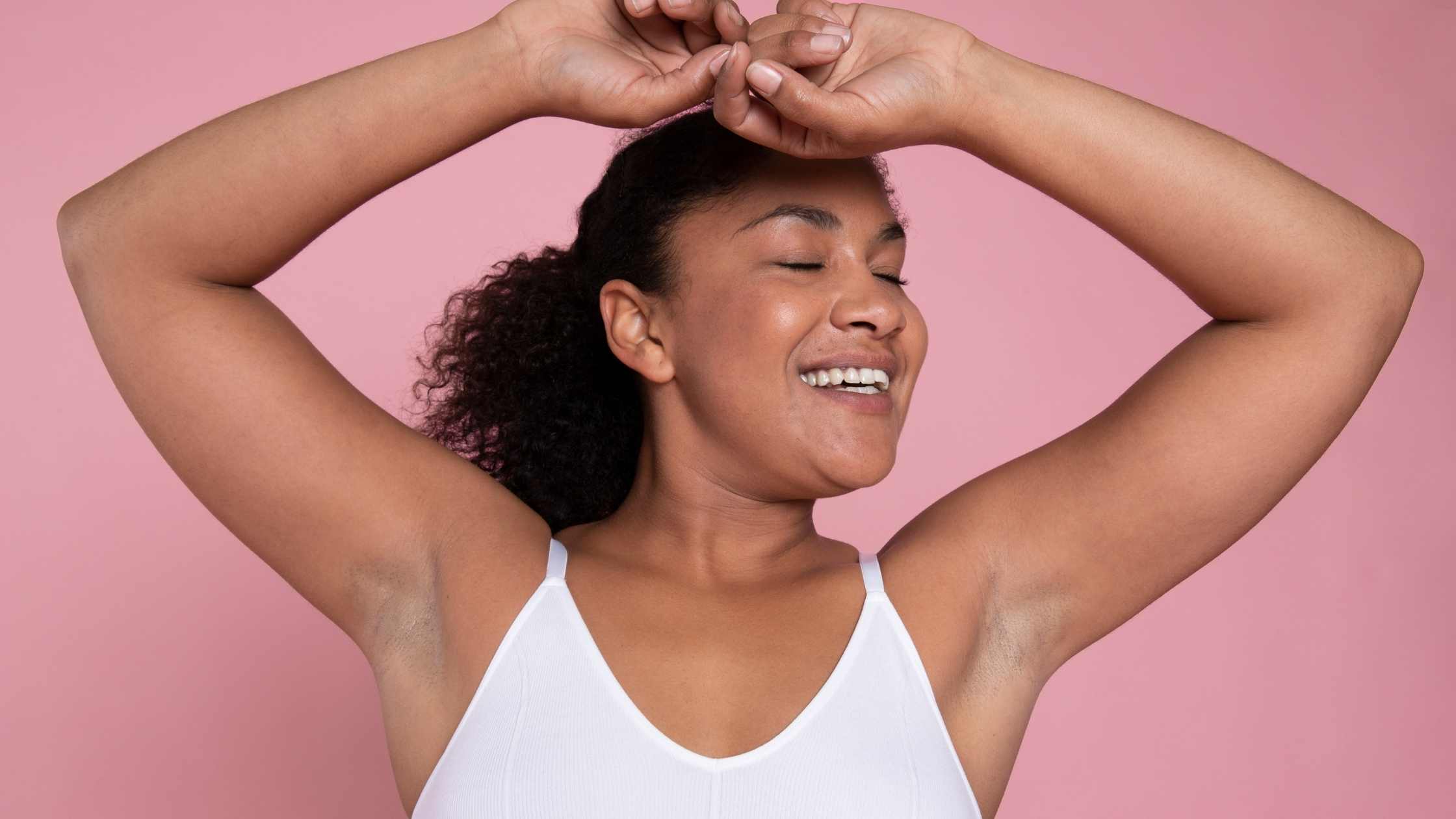 A woman with dark underarms happily opened her arms in the sky and putting her hands on her forehead.